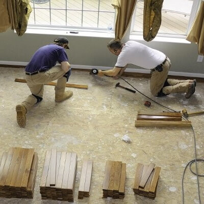 People repairing flooring near a window